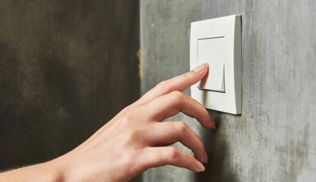 Hand pressing a light switch off.