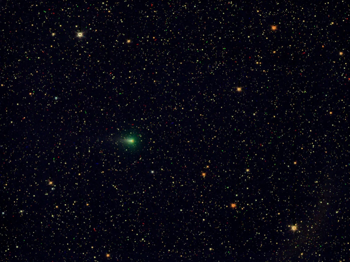 RGB deep-space color image of interstellar comet 3I/ATLAS showing its green coma amid a star field, captured by ESA's JUICE mission JANUS camera after perihelion in 2026.
