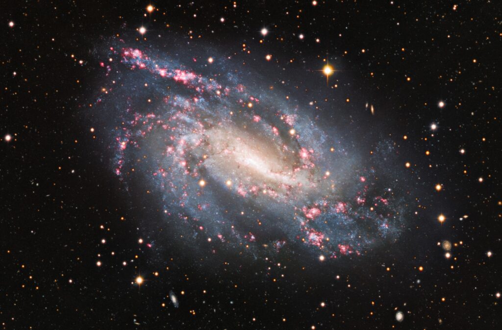 Composite optical image of the Amatha Galaxy (NGC 925), a barred spiral galaxy in Triangulum showing pink H II star-forming regions along its offset bar and spiral arms
