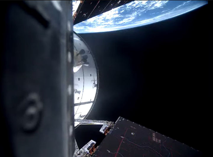 NASA Orion "Integrity" capsule seen from Artemis 2 in low Earth orbit, with Earth's blue atmosphere curving in the background — April 2026 lunar mission.