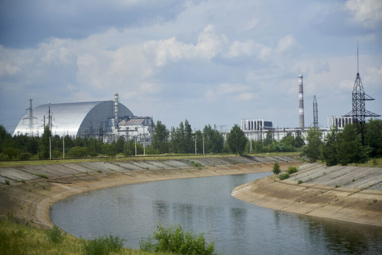 Chernobyl New Safe Confinement steel arch covering Reactor 4, with cooling canal and ventilation stack, 40 years after the 1986 nuclear disaster.