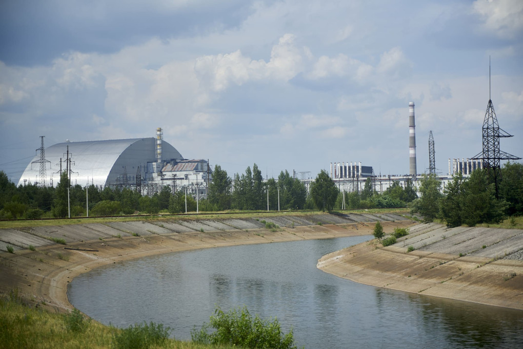 Chernobyl New Safe Confinement steel arch covering Reactor 4, with cooling canal and ventilation stack, 40 years after the 1986 nuclear disaster.