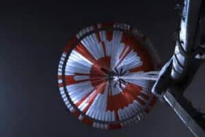 NASA Perseverance deploys its red-and-white supersonic parachute during descent through the Martian atmosphere