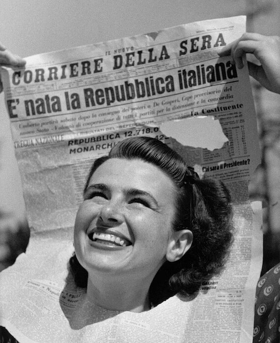 Smiling young Italian woman holding the Corriere della Sera front page "&Egrave; nata la Repubblica italiana" announcing Italy's Republic Day birth on June 2, 1946